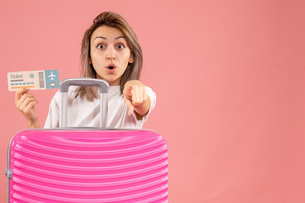 Wunderte sich junges mädchen mit rosa koffer mit ticket auf kamera gerichtet