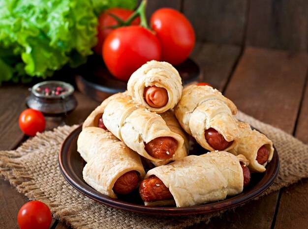 Wurst im Teig bestreut mit Sesam auf einem hölzernen Hintergrund im rustikalen Stil