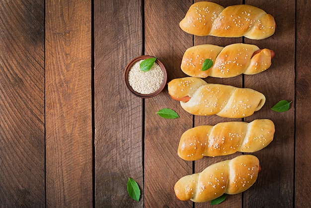 Kostenloses Foto wurst im teig mit sesam auf einem holztisch im rustikalen stil bestreut