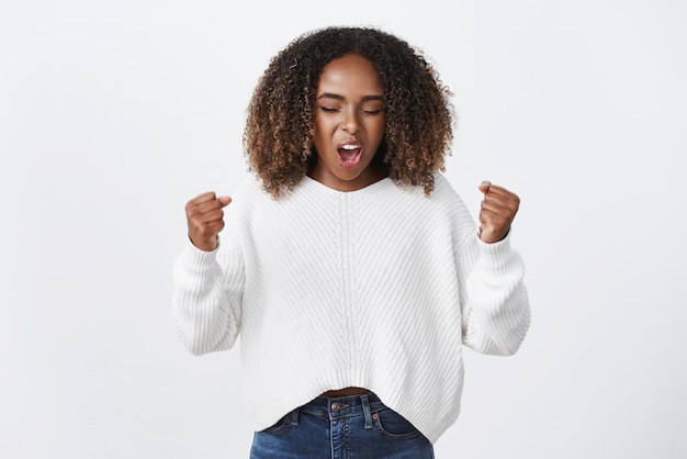 Yeah go Woman Power Porträt einer süßen emotionalen und aufgeregten charismatischen dunkelhäutigen Frau, die zur Unterstützung und Feier schreit und die Fäuste ballt, die das Selbstvertrauen ermutigen und stärken