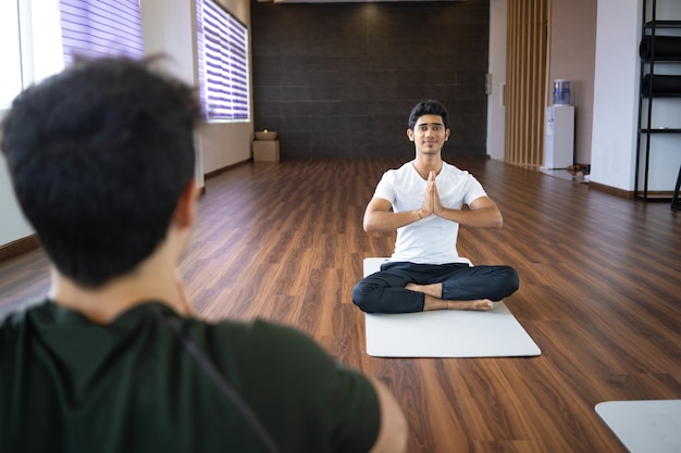 Kostenloses Foto yogalehrer, der mit studenten in der turnhalle meditiert