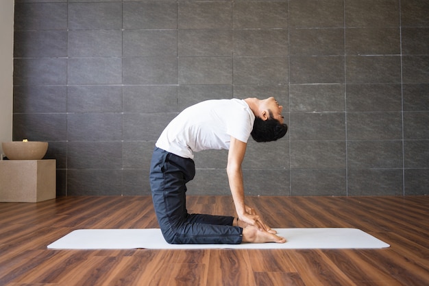 Yogi, der Kamelyogahaltung in der Turnhalle tut