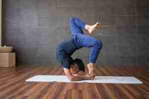 Kostenloses Foto yogi, der schwierige handstandyogahaltung in der turnhalle tut