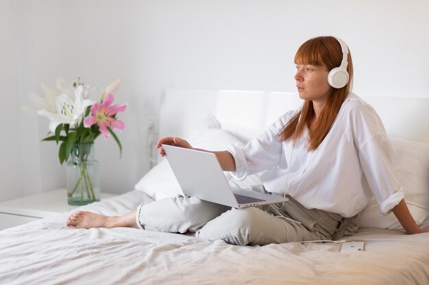 Yyoung mädchen hört musik und arbeitet am computer blumenlilie drinnen