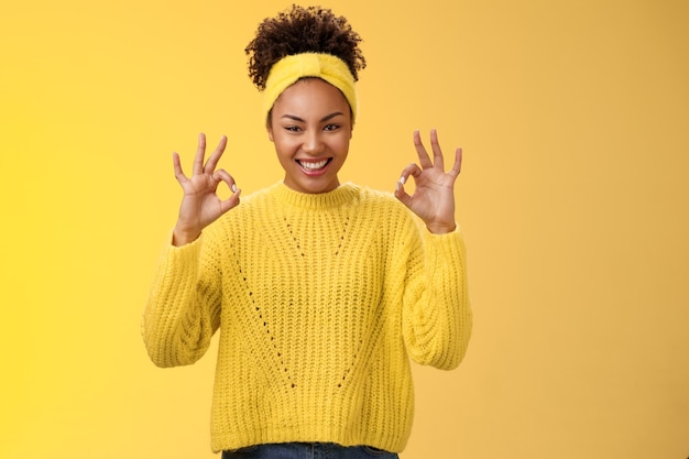 Zählen Sie es fertig. Zuversichtlich selbstbewusste afroamerikanische Frau in Pullover-Stirnband-Show okay ok keine Sorgen Geste lächelnd selbstbewusster Plan geht gut, freut sich über gute Ergebnisse, jubelnder gelber Hintergrund.