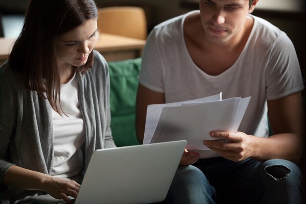 Zahlungsrechnungen der ernsten tausendjährigen Paare online auf Laptop zu Hause