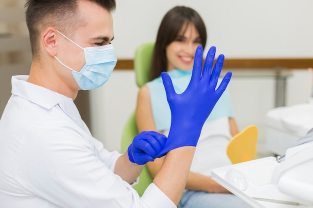 Zahnarzt, der chirurgische Handschuhe überzieht