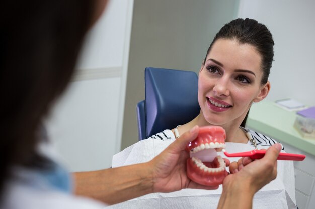 Zahnarzt, der dem Patienten einen Satz Modellzähne zeigt