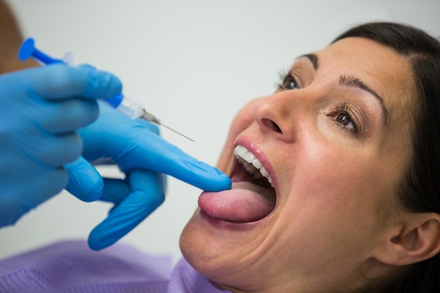 Zahnarzt, der der Patientin eine Injektion gibt