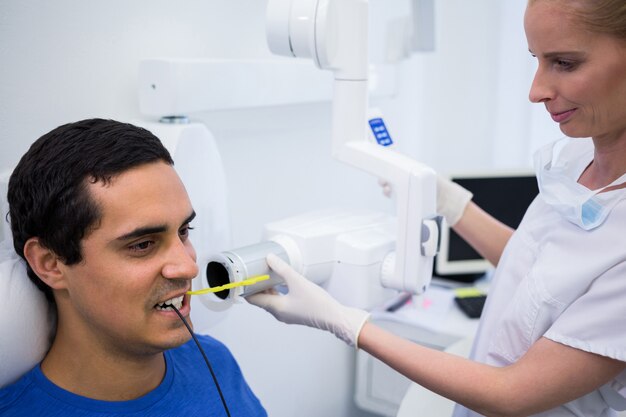 Zahnarzt, der eine männliche Röntgenaufnahme des Zahns des Patienten nimmt