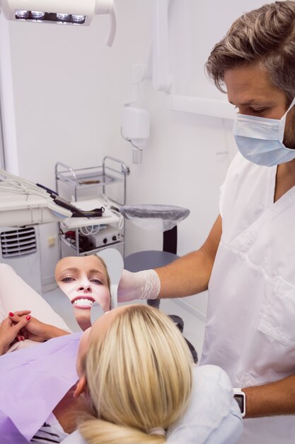 Zahnarzt, der einen Spiegel nahe Gesicht des Patienten hält