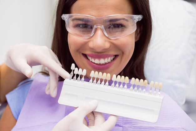 Zahnarzt, der Patientin mit Zahnfarben untersucht