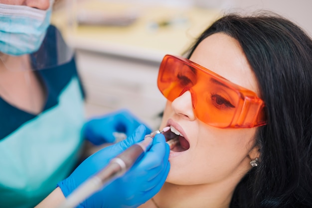 Zahnarzt, der Zähne des Patienten in den Gläsern kuriert