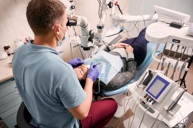 Zahnarzt untersucht Frauenzähne mit diagnostischem Mikroskop