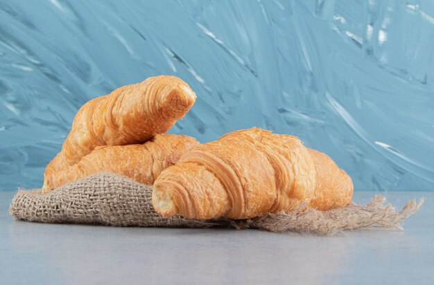 Zahnhafte Croissants auf Handtuch, auf dem blauen Hintergrund. Hochwertiges Foto