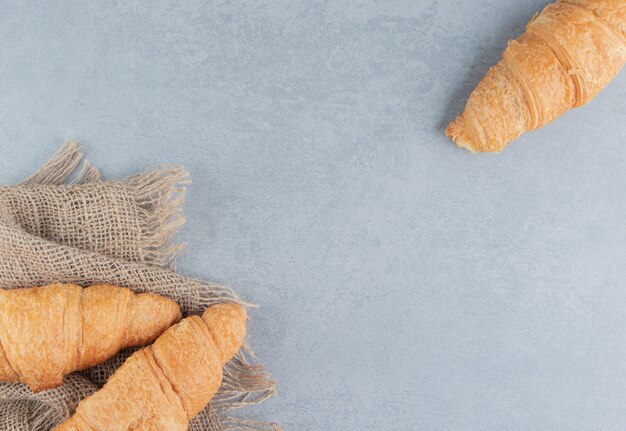 Zahnhafte Croissants auf Handtuch, auf dem Marmorhintergrund. Hochwertiges Foto