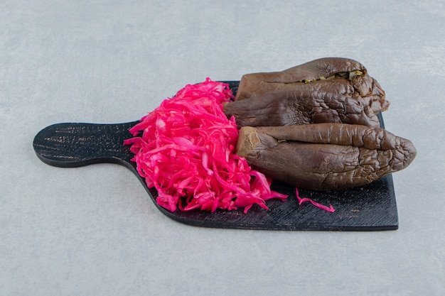 Zahnige Aubergine und eingelegter Rotkohl auf dem Schneidebrett auf der Marmoroberfläche