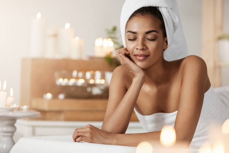 Kostenlose Foto zarte afrikanische frau mit handtuch auf kopfruhe entspannend im spa-salon.