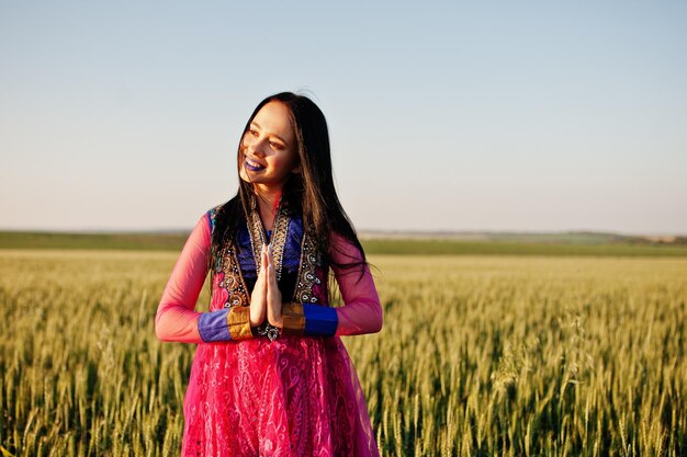 Zartes indisches Mädchen in Saree mit violetten Lippen Make-up bei Sonnenuntergang auf dem Feld gestellt Modisches Indien-Modell