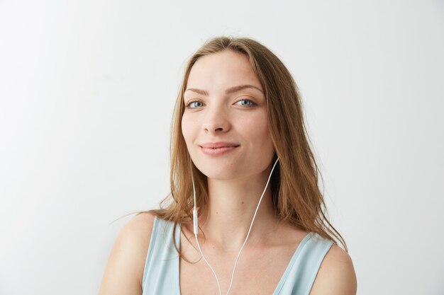 Zartes junges hübsches Mädchen lächelnd, das Streaming Musik in Kopfhörern hört.