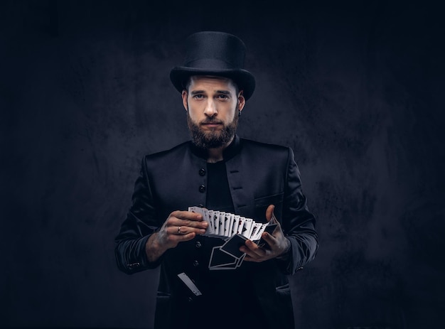 Zauberer zeigt Trick mit Spielkarten auf dunklem Hintergrund.