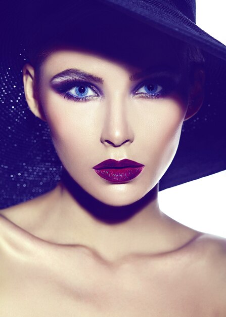 Zaubernahaufnahmeporträt des schönen sexy stilvollen Modells der jungen Frau mit hellem Make-up mit den roten Lippen mit perfekter sauberer Haut im zufälligen Stoff im Hut