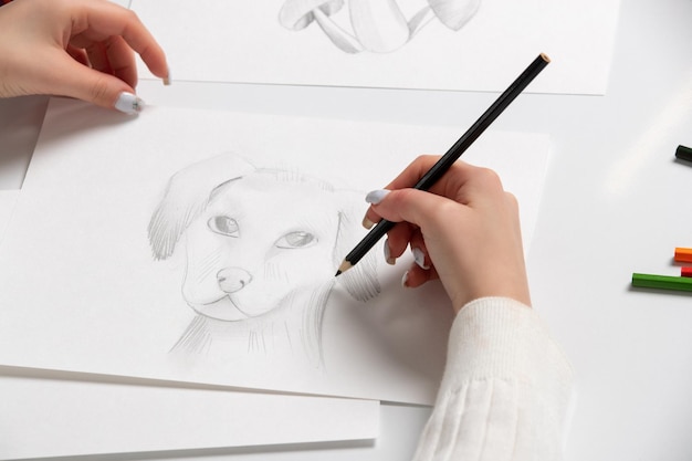 Zeichnen einer Hand eines jungen Mädchens, die einen niedlichen Hund mit dem schwarzen Bleistift zeichnet