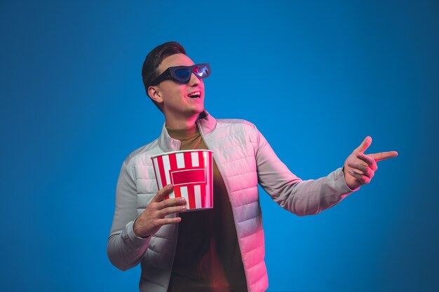 Zeigen in 3D-Brillen und mit Popcorn. Porträt des kaukasischen Mannes isoliert. Schönes männliches Model.