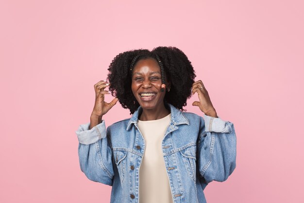 Zeigen. Porträt der schönen Frau des Afroamerikaners lokalisiert auf rosa Wand mit Exemplar. Stilvolles weibliches Modell. Konzept der menschlichen Emotionen, Gesichtsausdruck,