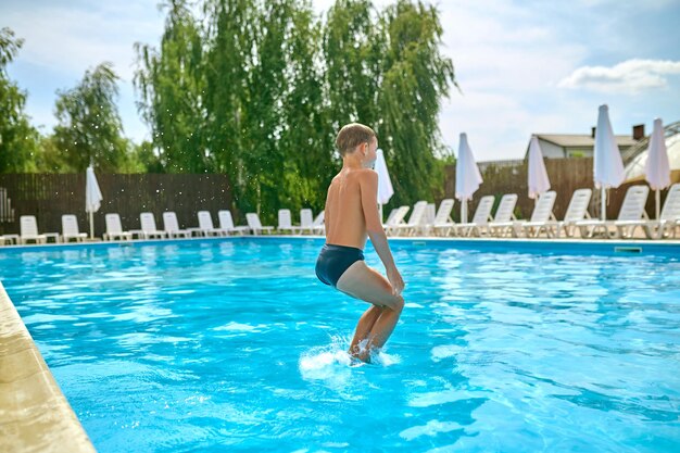 Zeigen Sie die Rückseite des Jungen an, der in den Pool springt