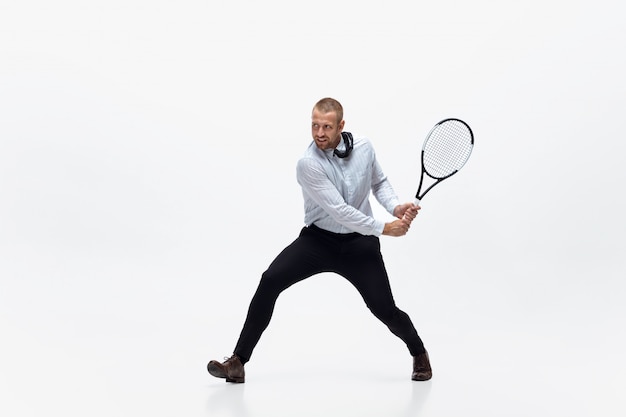 Zeit für Bewegung. Mann in Bürokleidung spielt Tennis isoliert auf Weiß. Geschäftsmann Training in Bewegung, Aktion. Ungewöhnlicher Look für Sportler, neue Aktivität. Sport, gesunder Lebensstil.