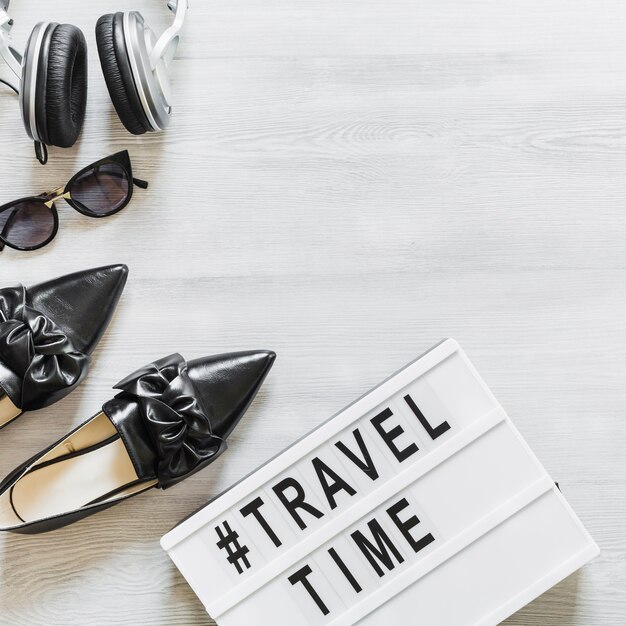 Zeit- und Reisetext mit Schuhen, Brillen und Kopfhörer auf Schreibtisch