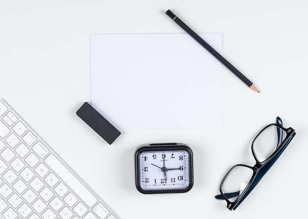 Zeitmanagementkonzept mit Uhr, Bleistift, Radiergummi, Brille, Papier, Tastatur auf weißem Hintergrundraum für Text, Draufsicht. horizontales Bild