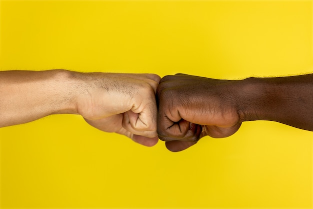 Zentralansicht der europäischen und afroamerikanischen Hand zu Hand zu Fäusten geballt