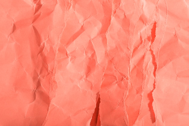 Zerknitterte Papierstruktur auf korallenrotem Hintergrund