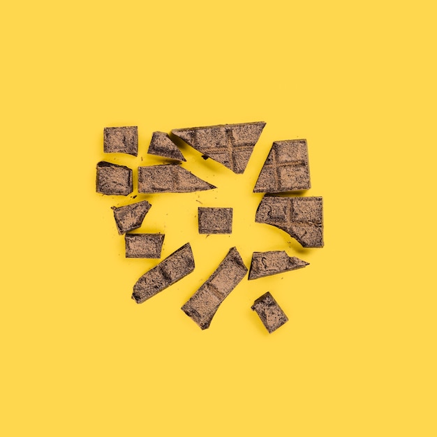 Zertrümmerte Stücke Schokolade auf gelber Oberfläche