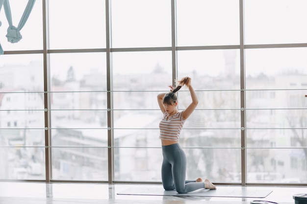 Ziemlich attraktives Mädchen, das Yoga in einem hellen Raum tut