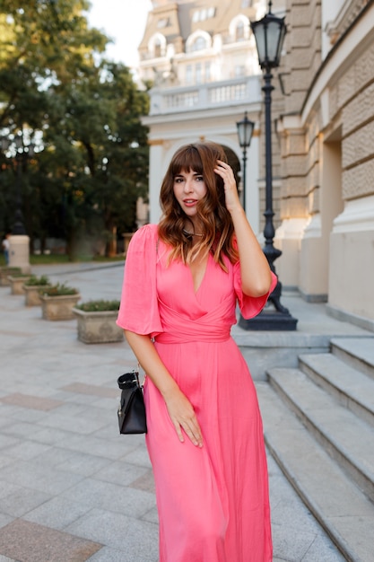 Ziemlich romantische Frau im rosa Kleid, das im Freien in der alten europäischen ity aufwirft.