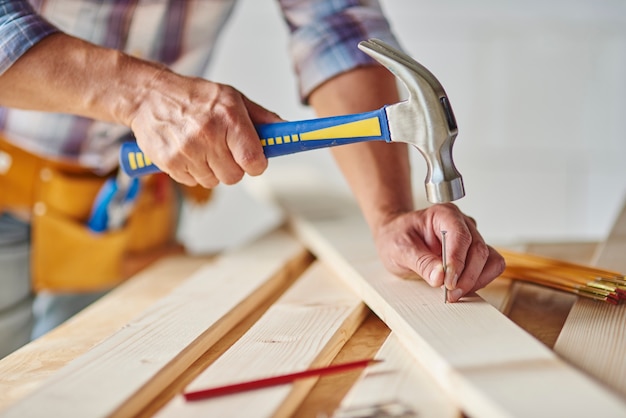 Zimmermann mit Hammer auf Nägel schlagen