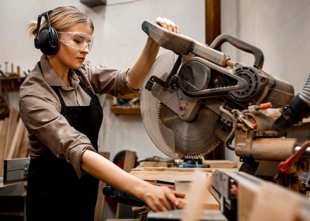 Zimmermannsfrau mit elektrischer Säge im Studio