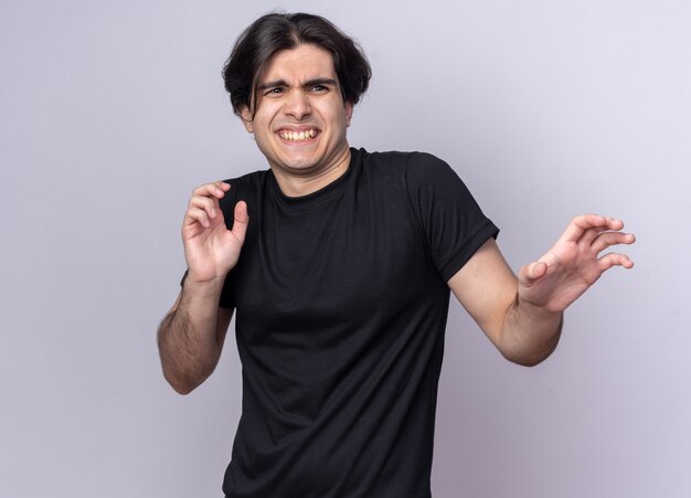 Zimperlicher Blick auf den jungen gutaussehenden Mann der Seite, der das schwarze T-Shirt trägt, das die Hände an der Seite isoliert auf weißer Wand hält