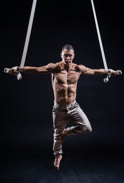 Zirkusartist auf den luftbändern mit starken muskeln auf schwarzem hintergrund Premium Fotos