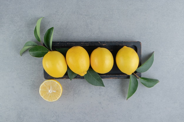 Zitronen auf einem kleinen Tablett mit Blättern auf Marmor geschmückt