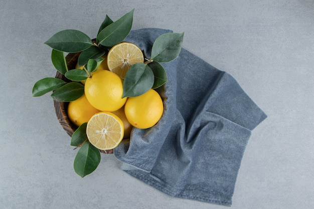 Zitronen und Blätter in einem Eimer auf Marmor gestapelt