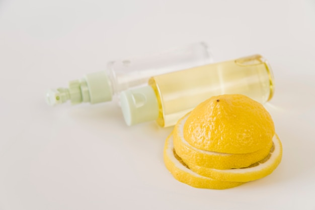 Zitronenscheiben und Sprühflaschen auf weißem Hintergrund