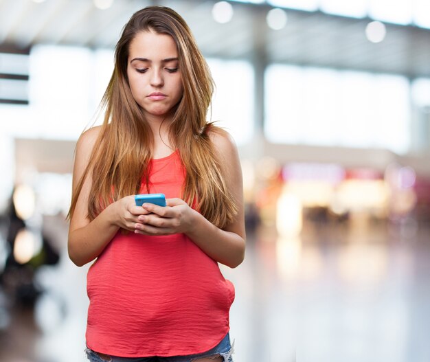 zornige junge Frau, die einen Text auf Handy auf weißem eingeben