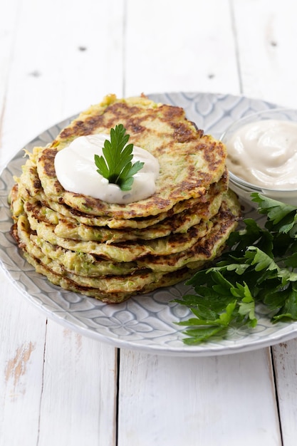 Kostenloses Foto zucchini-krapfen mit joghurtsauce auf weißem holztisch