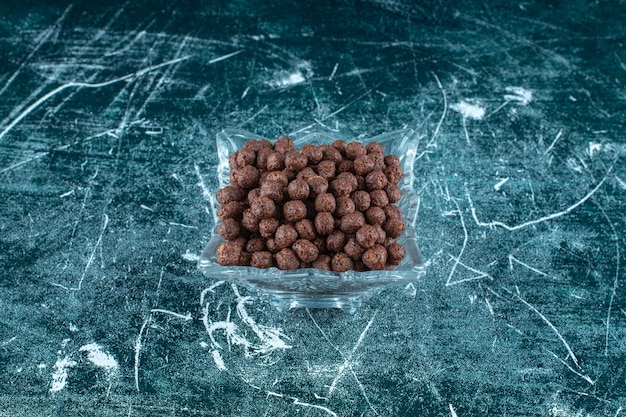 Zuckermaisbällchen in einer Glasschüssel, auf blauem Hintergrund. Foto in hoher Qualität