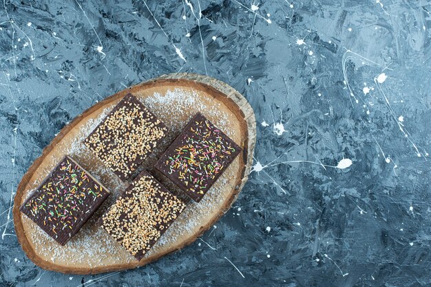 Zuckerstreusel auf einer Schokoladenwaffel auf einem Brett, auf dem blauen Tisch.