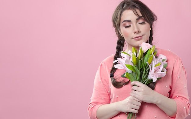 Zufriedene aufwerfende Frau beim Halten des Blumenstraußes der Lilien in den Händen